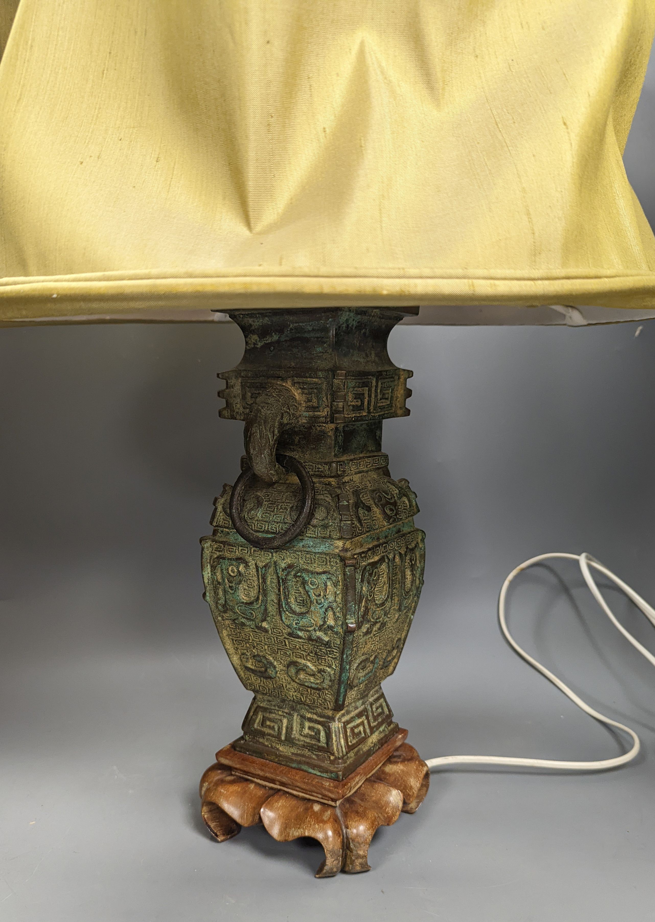 A pair of Chinese archaistic bronze lamps, 37 cms high not including shades or light fitting.